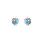 A pair of handmade opal stud earrings by Emily Eliza Arlotte, featuring light blue opals and an engraved textured halo, on a white background.