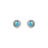 A pair of handmade opal stud earrings by Emily Eliza Arlotte, featuring light blue opals and an engraved textured halo, on a white background.