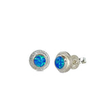 A pair of handmade opal stud earrings by Emily Eliza Arlotte, featuring a blue opals and an engraved textured halo, on a white background.