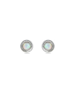 A pair of handmade opal stud earrings by Emily Eliza Arlotte, featuring white opals and an engraved textured halo, on a white background.