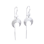 Lunar Thread Earrings on a white background. These sterling silver earrings feature a textured disc and crescent moon hanging from a hook and fine chain fitting.
