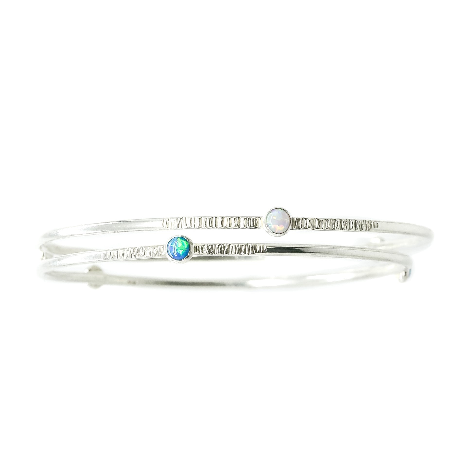 Two Sterling Silver Opal Bangles that have a textured finish sit on a white background.