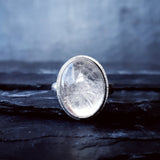 A large quartz stone set in the Prescience Ring by Emily Eliza Arlotte sits on layers of dark slate stone.