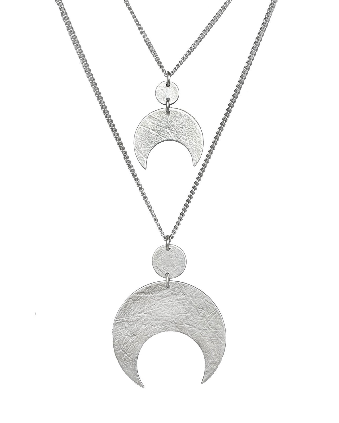 Two crescent moon sterling silver necklaces hang on a white background. The silver moon and circle above it are textured and are handmade by Emily Eliza Arlotte in Hobart, Tasmania.