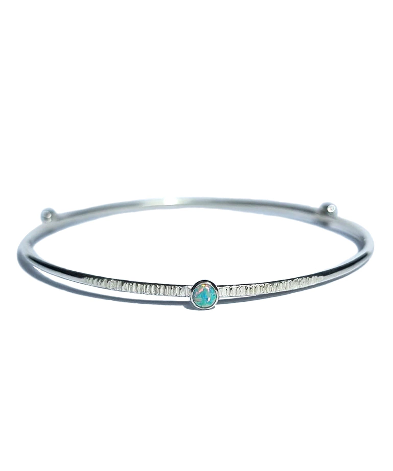 A Sterling Silver Opal Bangle with a textured finish sits on a white background.