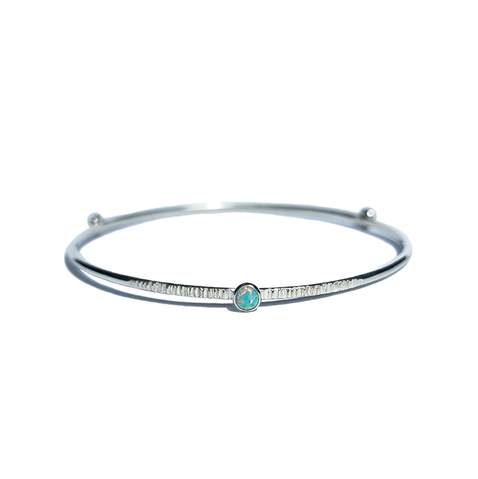 A Sterling Silver Opal Bangle with a textured finish sits on a white background.