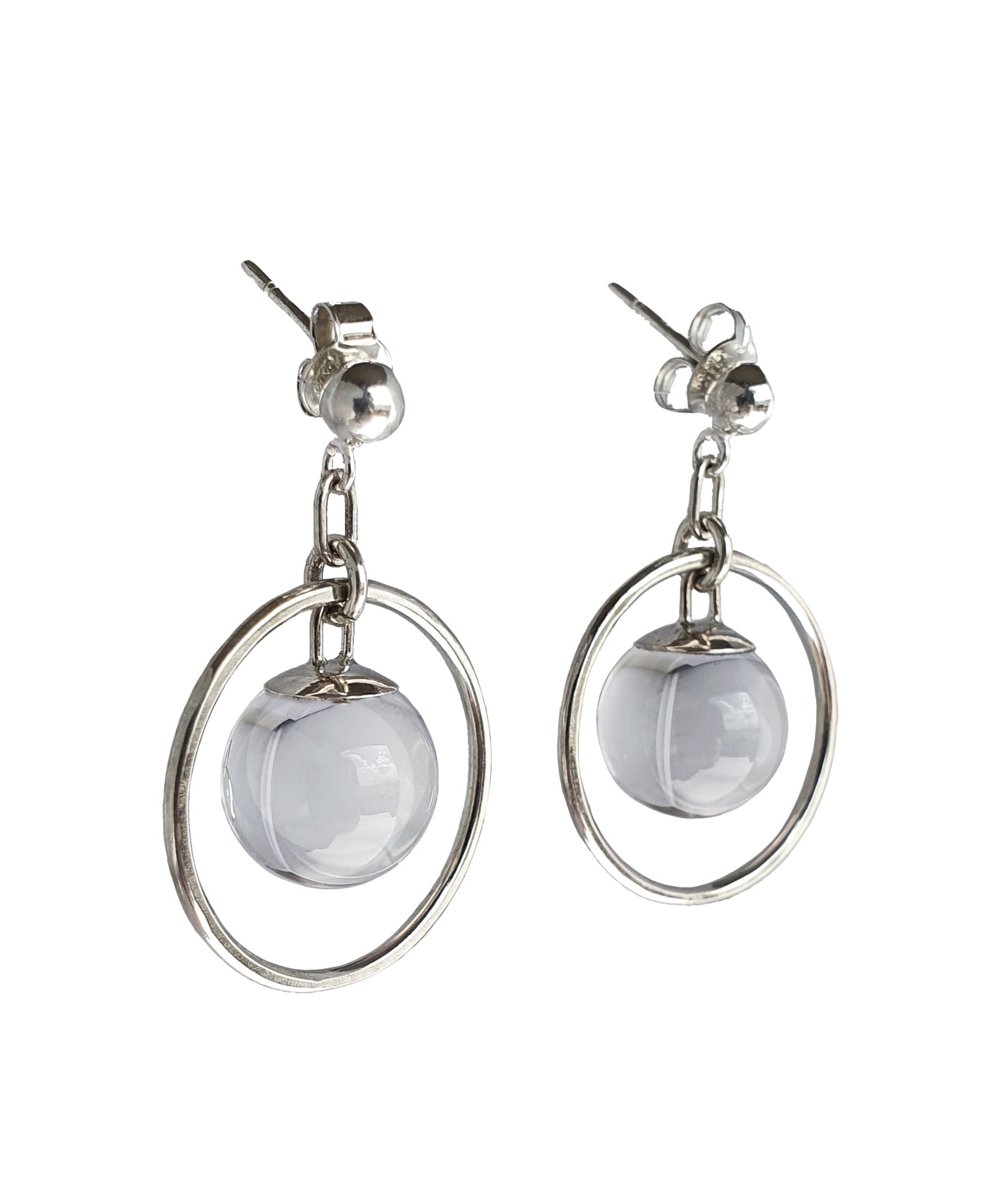 A side view of the Divination Stud Earrings in Sterling Silver featuring a Quartz Crystal Ball in inside a hoop design. Set on a white background.