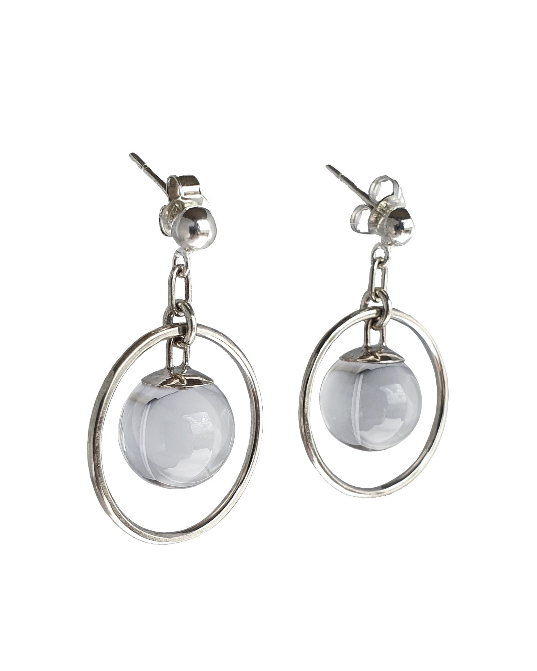 A side view of the Divination Stud Earrings in Sterling Silver featuring a Quartz Crystal Ball in inside a hoop design. Set on a white background.